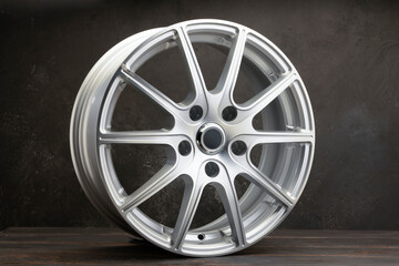 new grey alloy wheels on a dark textured black background. a wheel for a car
