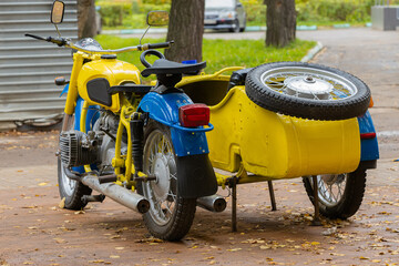 Yellow Soviet police motorcycle Ural with sidecar in urban park. Back view