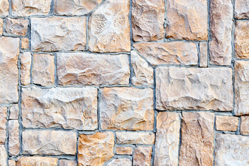 Cobble brown stone siding tile wall abstract background. House exterior with blocks tiled with cement . Crafted brickwork outer wall.