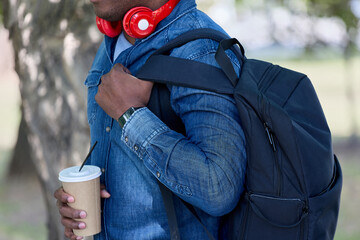 Dark-skinned man participates in a tour of a large nature reserve with a backpack and a glass of...