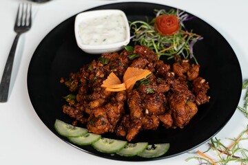 Delicious juicy Teriyaki with sauce and groceries on a black plate on a table
