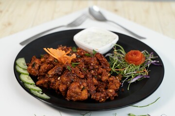 Delicious juicy Teriyaki with sauce and groceries on a black plate on a table