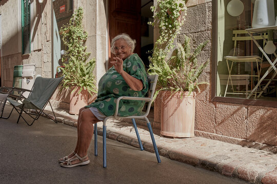 Mujer senior sentada saluda alegre a los turistas en una calle