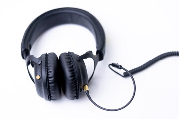 Headphones, cover, black leather, stereo jack, coiled on a white background.