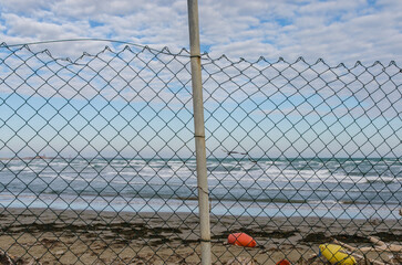 Panorama del mare in burrasca visto da dietro una rete nell’isola di Ca’ Roman a Pellestrina 