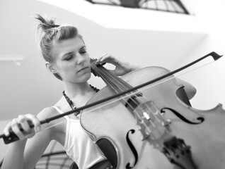 Young woman playing violoncello on the stage in black and white