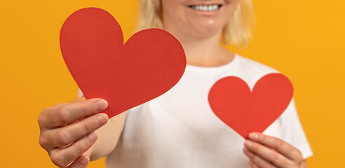 widescreen image of two hearts in the hands of a happy woman. valentines day concept