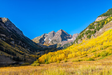 Fototapeta premium Aspen, Colorado Maroon Bells rocky mountains in October fall autumn season with yellow golden trees foliage and clear blue sky in morning sunrise with nobody