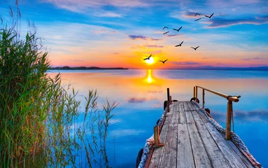 Foto op Plexiglas Atardecer en el lago con viejo un embarcadero de madera  © kesipun