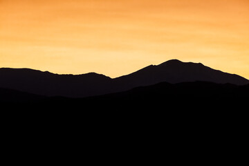 Yellow orange pastel sunset in Aspen, Colorado with rocky mountains peak in autumn and vibrant color at twilight with mountain ridge dark silhouette