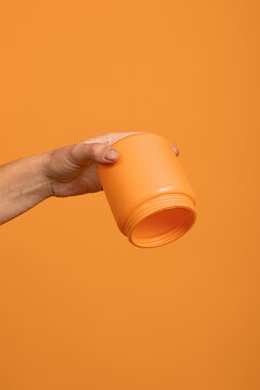 upside down empty yellow bottle in hand on orange background