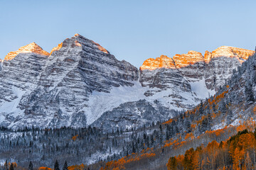 Maroon Bells at sunrise in Aspen, Colorado of Elk range mountain with Rocky mountains in late autumn with winter snow covered peak and sunlight light