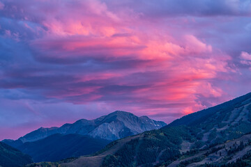Pink purple sunset in Aspen, Colorado with Rocky mountains of Buttermilk ski slope mountain in autumn with twilight sunset and cumulus clouds