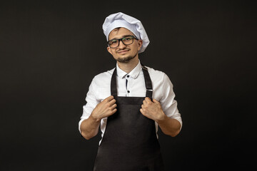 smiling chef looking at camera holding his apron on black background