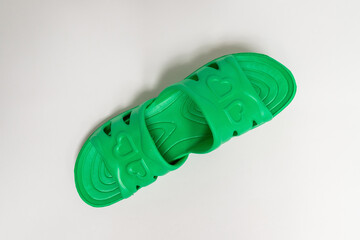 Green, rubber slippers for a bath on a gray background, viewed at 45 Â°.