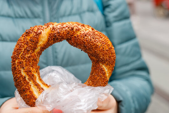 woman holds a traditional Turkish simit in hands and wants to eat it