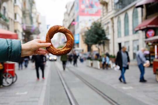 Turkish bread simit in hand. Traditional baked bagel in Turkey sold as street food and eaten with tea for breakfast or lunch