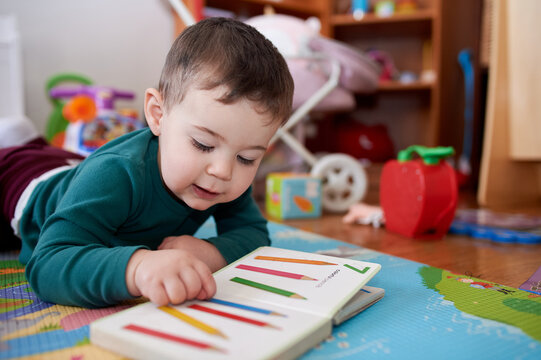 young boy playing and looking at books in his room