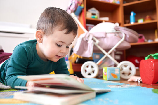 young boy playing and looking at books in his room