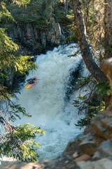 Vertical shot of extreme kayaking over massive waterfall