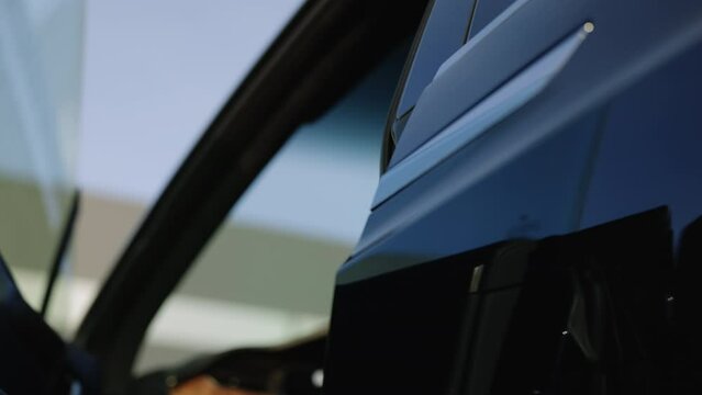 Male hand opening car door handle. Unrecognizable man buying vehicle in dealership. Man in black suit opens black electric car door. Success and lifestyle. People and transportation. VIP service