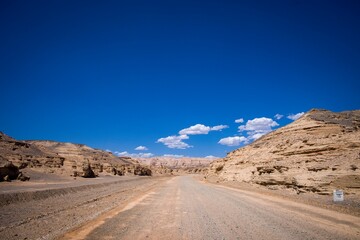 Beautiful view of a gravel road line by rocky cliffs