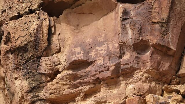 Panning desert cliffs with various rock art petroglyphs on them from Native Americans in Nine Mile Canyon.