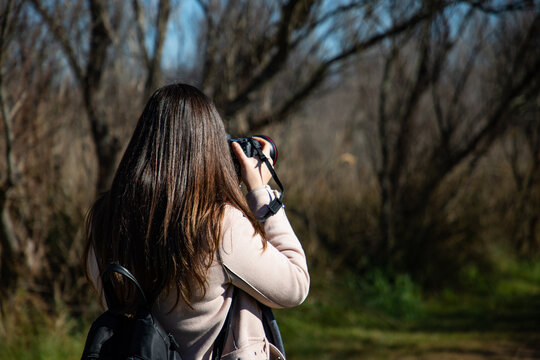 Beautiful woman taking a picture of a dry trees forest