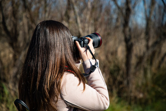 Beautiful woman taking a picture of a dry trees forest