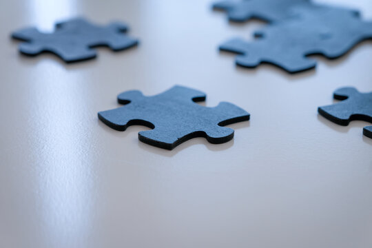 Dark blue jigsaw puzzle pieces on white backround ready to be placed. Negative space for copy at bottom of image.