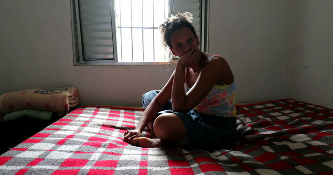 Casual Brazilian Woman Sitting In Bed At Home. Pensive Thoughtful Person