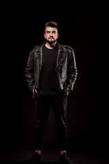Fototapeta na wymiar portrait of a man in a leather jacket and in the studio on a black background