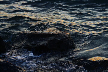 blue waves hitting rocks during golden hour