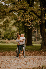 Fototapeta premium Grandfather spending time with his granddaughter in park on autumn day