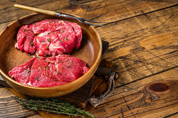 Fresh Mutton chop leg steaks, uncooked lamb meat with herbs. Wooden background. Top view. Copy space