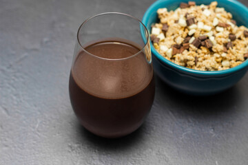Sweet chocolate granola cereals  and chocolate milk, in a blue bowl on a black background