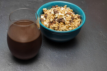 Sweet chocolate granola cereals  and chocolate milk, in a blue bowl on a black background