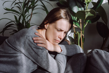 Close up of thoughtful stressed young girl sit on couch looking in distance, considering...