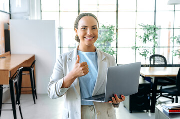 Beautiful positive confident hispanic or brazilian woman, seo, manager, stands in the office in...
