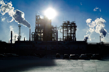 Oil refinery plant against the backdrop of bright winter sun.