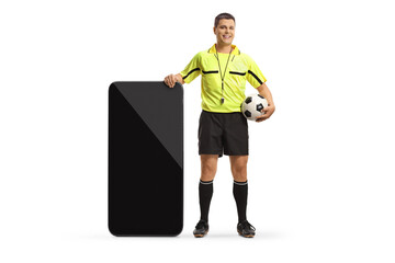 Full length portrait of a football referee standing next to a big smartphone