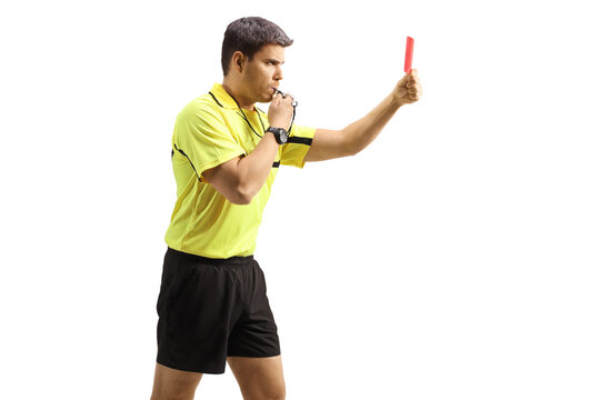 Profile shot of a football referee blowing a whistle and showing a red card