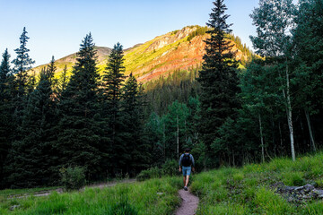 Man hiker walking on green alpine footpath trail to Ice lake near Silverton, Colorado in August...