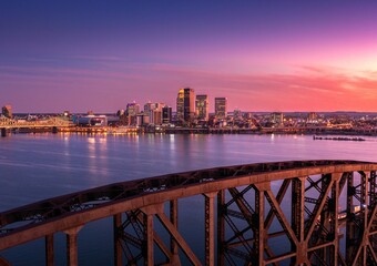 Aerial view of cityscape Louisville surrounded by buildings and water during sunset