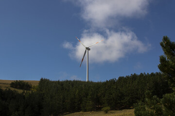 Fototapeta na wymiar A wind farm or wind park with wind turbine located in the mountains of Italy Europe and it allows to realize clean energy. It’s sustainable, renewable energy for enviromental