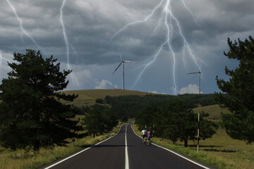 Wind turbines. Bikers go to mountain wind farm in Italy. Renewable energy concept, green energy...