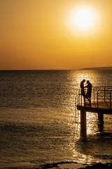 Fototapeta premium Silhouette of young couple enjoying beautiful sunset at the beach. Romantic moment human relationship