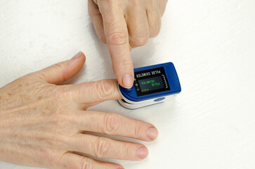 Close-up of a pulse oximeter on the finger of an elderly woman