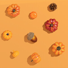 Trendy Autumn sunny composition made with pumpkins and seasonal fruits, on sunlit orange pastel background with sharp shadows. Flat lay harvest or halloween concept.