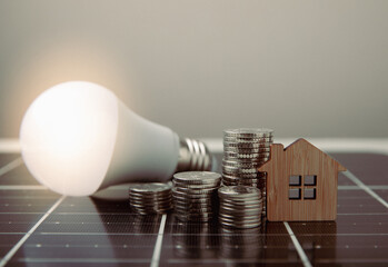 Solar panel on the background of house model, LED lamp and coins. Concept of saving money and clean...